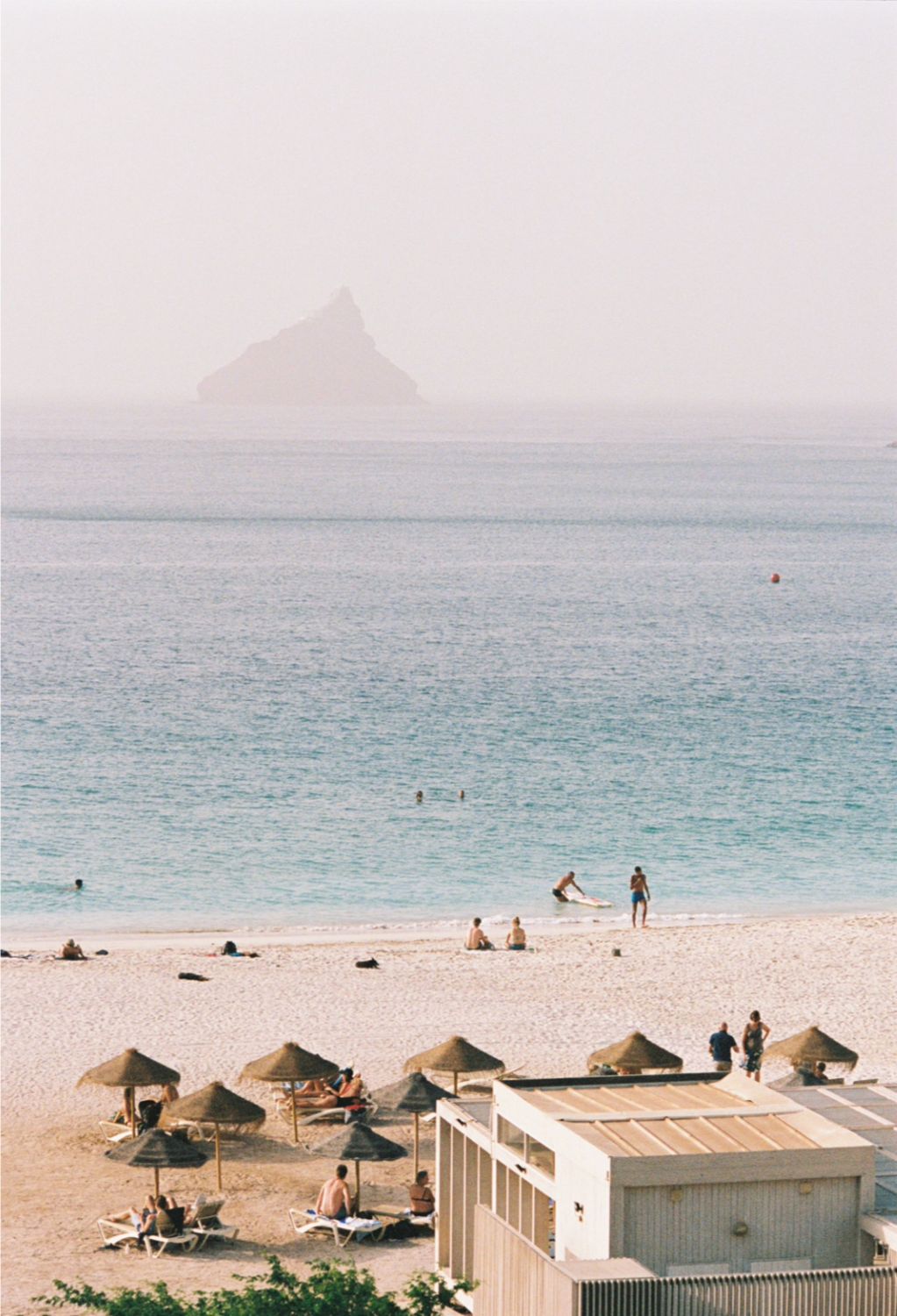 Laginha Beach with parasols and a rock in the haze