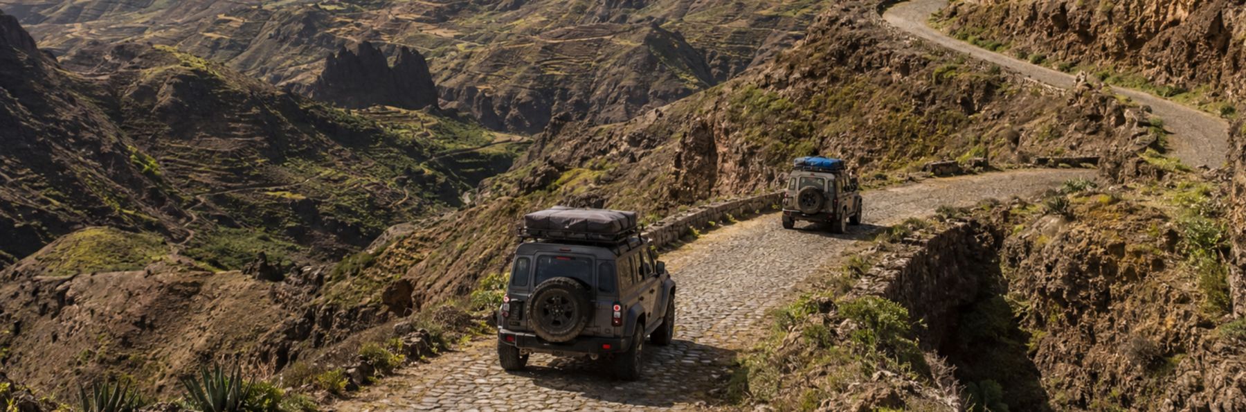 Two SUVs on the cobblestone Estrada da Corda