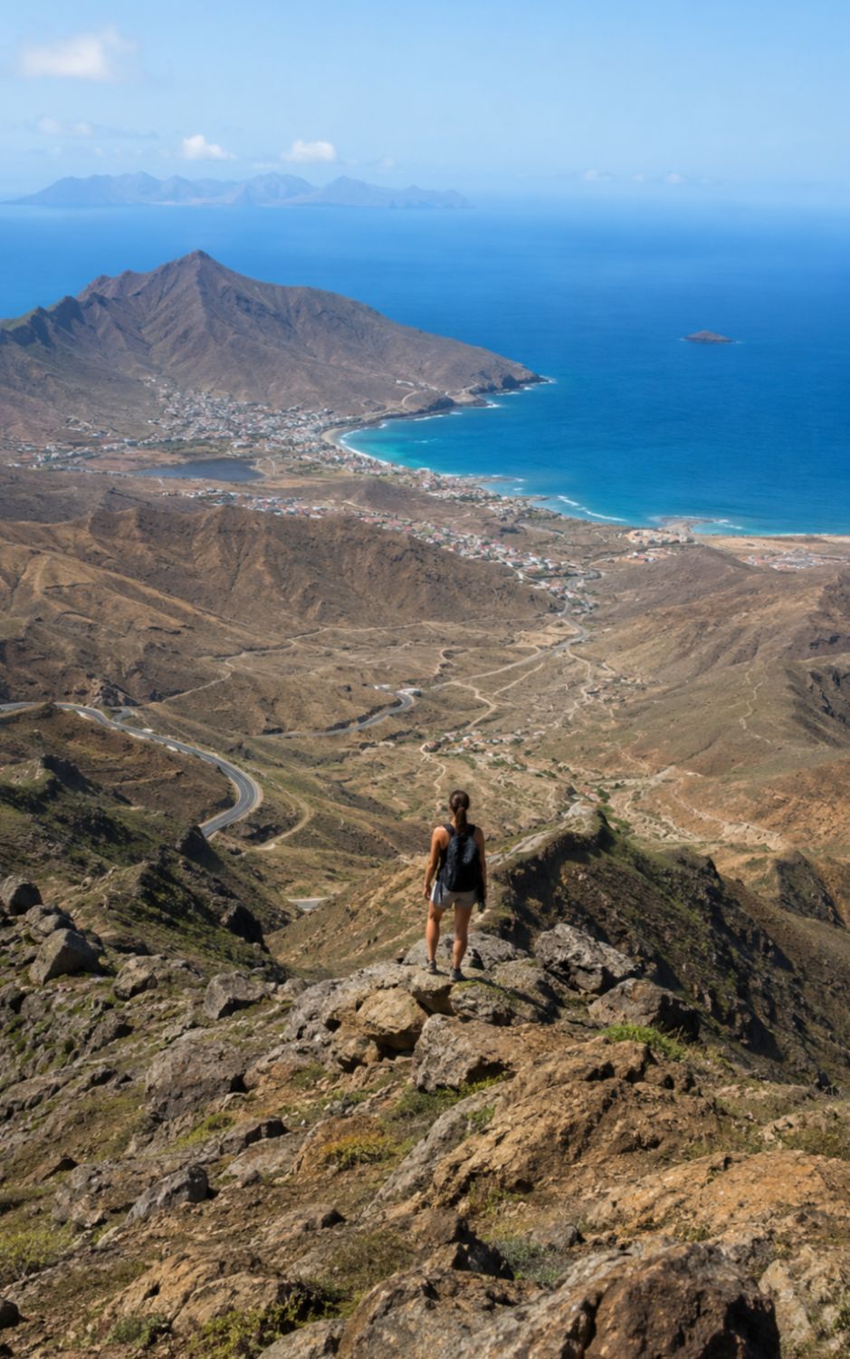 Hiker on a ridge above a bay and winding road